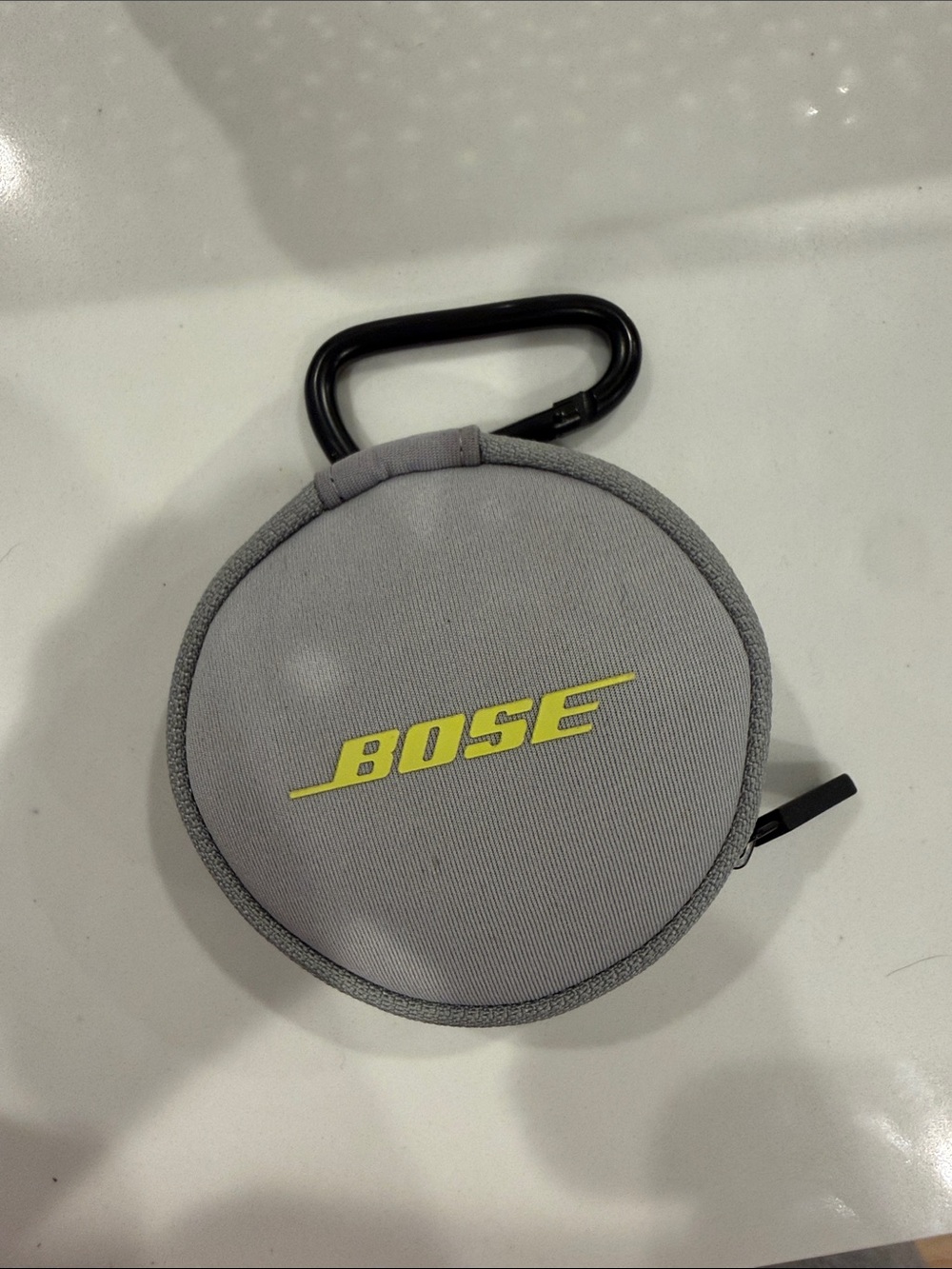 Bose Light Gray Round Earbud Case with Yellow Logo and Black Carabiner